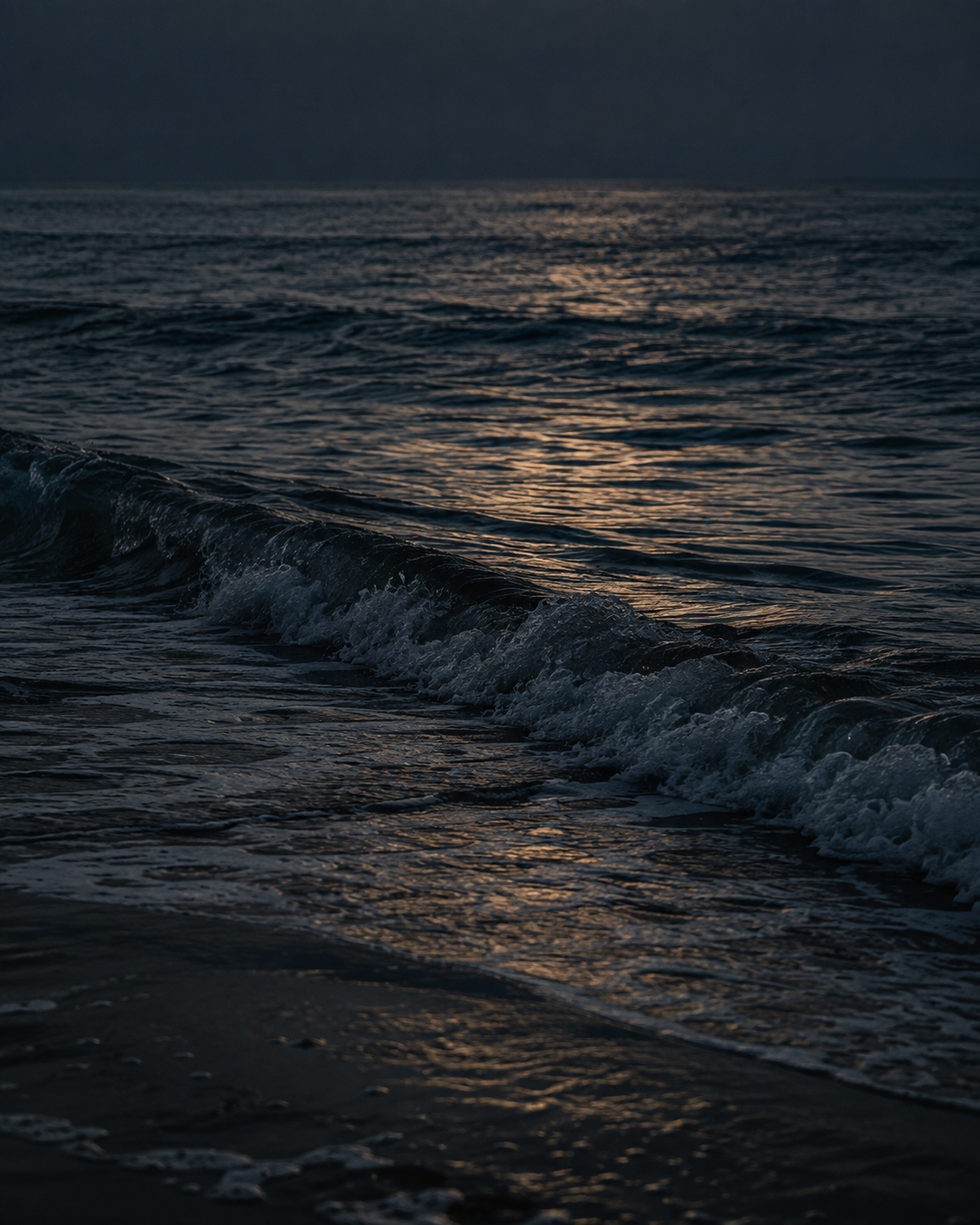 Amber dusk reflected on dark coastal waves